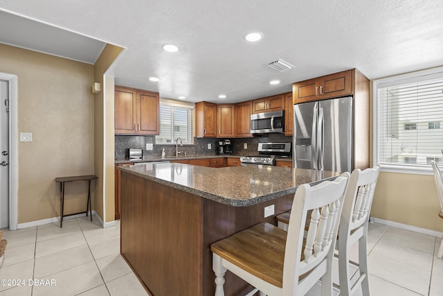 815 Ocean Shore Blvd Unit U1B, Ormond Beach, FL 32176 - kitchen featuring appliances with stainless steel finishes, baseboards, light tile patterned floors, tasteful backsplash, and brown cabinetry