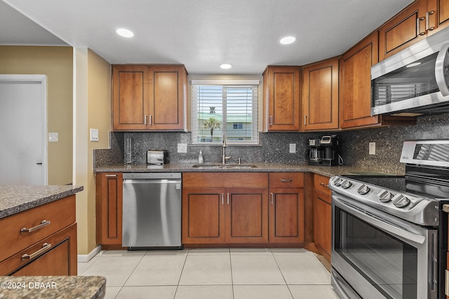 815 Ocean Shore Blvd Unit U1B, Ormond Beach, FL 32176 - kitchen featuring stainless steel appliances, a sink, brown cabinetry, decorative backsplash, and light tile patterned floors