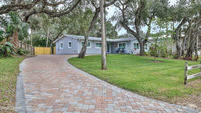 ranch-style house featuring decorative driveway, a front lawn, and fence