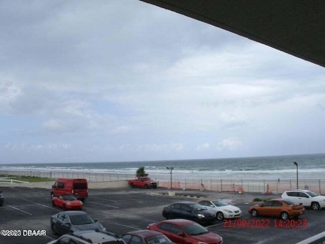 view of parking featuring a water view and a view of the beach