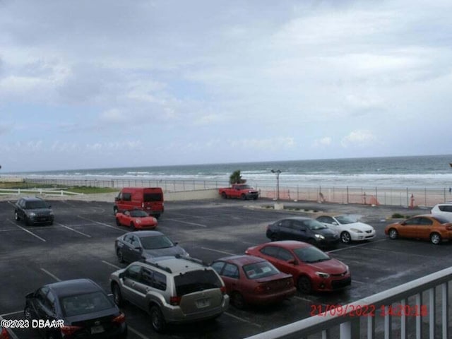 view of vehicle parking with a water view and a beach view