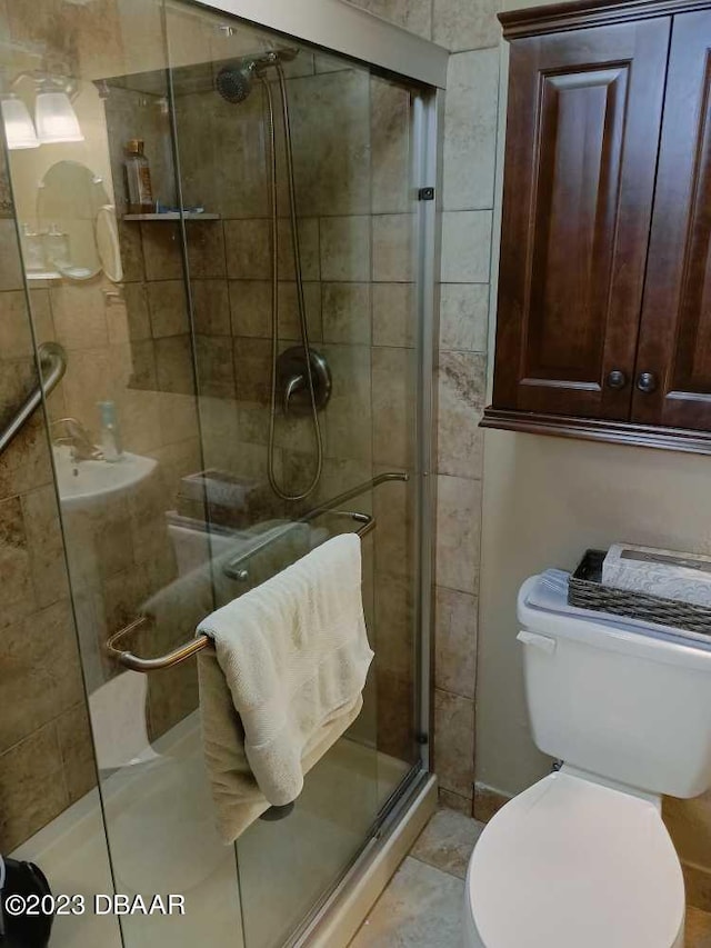 bathroom with a shower with shower door, tile patterned floors, and toilet