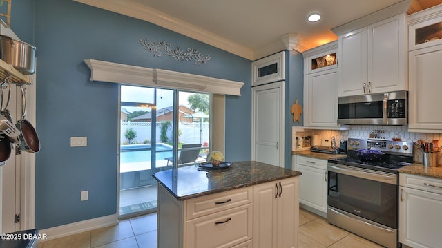 3368 Marsili Ave, New Smyrna Beach, FL 32168 - kitchen with stainless steel appliances, light tile patterned floors, tasteful backsplash, crown molding, and white cabinets