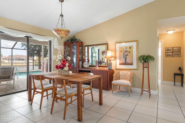 dining room featuring light tile patterned floors, baseboards, vaulted ceiling, and a healthy amount of sunlight