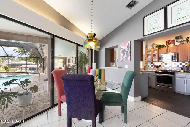 dining area featuring visible vents, light tile patterned floors, and lofted ceiling