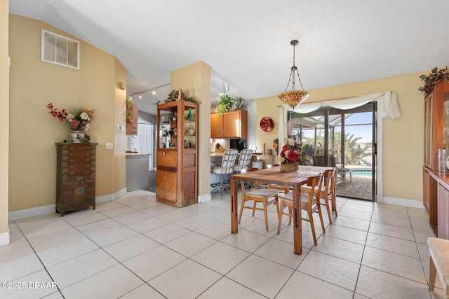 dining area with light tile patterned flooring, baseboards, lofted ceiling, and visible vents