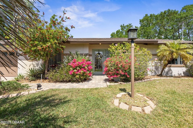view of front of property with french doors, a front lawn, and stucco siding