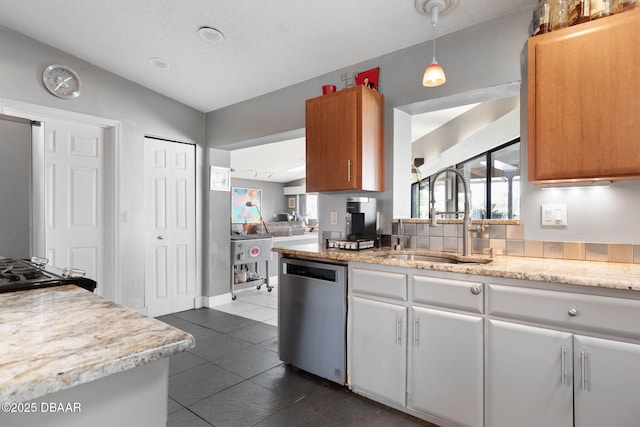 kitchen featuring pendant lighting, dark tile patterned flooring, dishwasher, a sink, and lofted ceiling