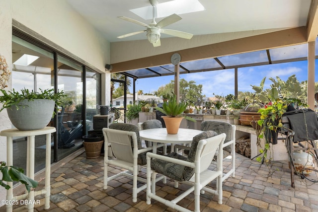 sunroom / solarium with a ceiling fan, a skylight, and outdoor dining area