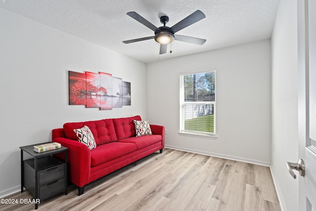 living room with ceiling fan, a textured ceiling, and light hardwood / wood-style floors