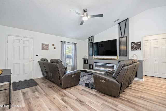 living room featuring ceiling fan, a textured ceiling, light wood-type flooring, and vaulted ceiling