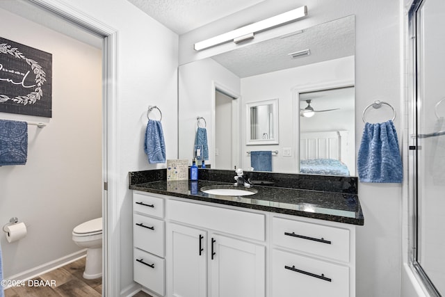 full bathroom with toilet, hardwood / wood-style floors, a textured ceiling, vanity, and ceiling fan