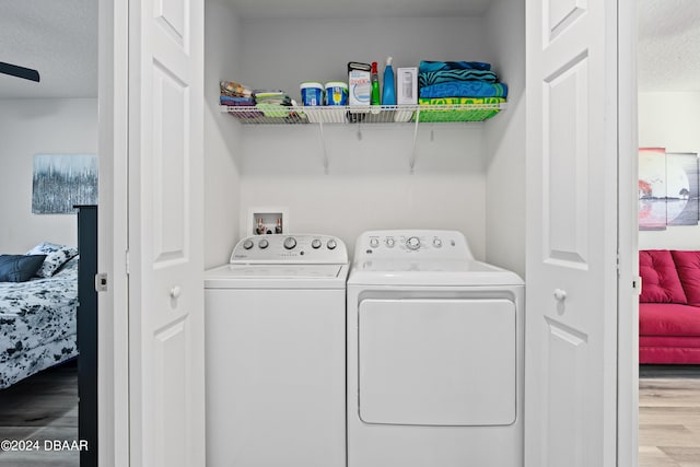 laundry area with washing machine and clothes dryer, light hardwood / wood-style floors, ceiling fan, and a textured ceiling