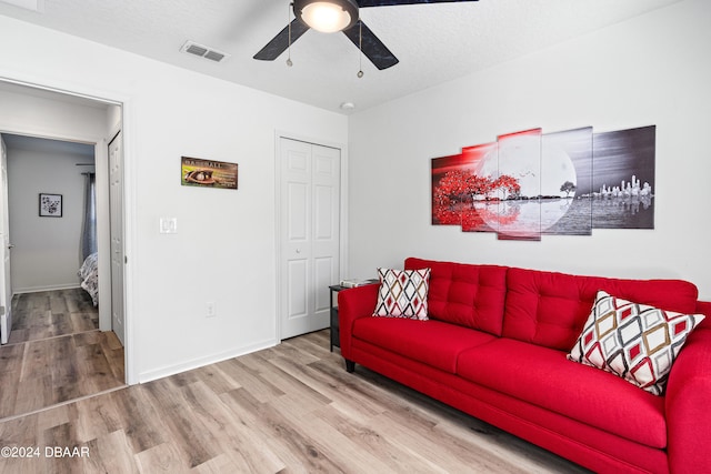 living room with hardwood / wood-style floors, ceiling fan, and a textured ceiling