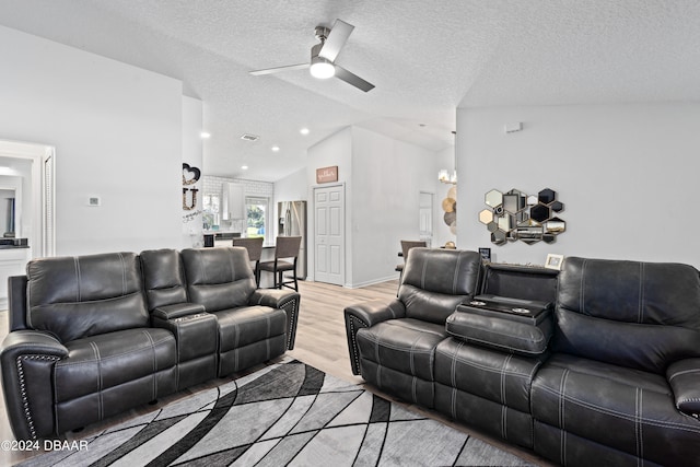 living room with a textured ceiling, light wood-type flooring, vaulted ceiling, and ceiling fan with notable chandelier