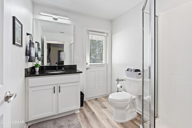 bathroom with wood-type flooring, toilet, a textured ceiling, vanity, and walk in shower