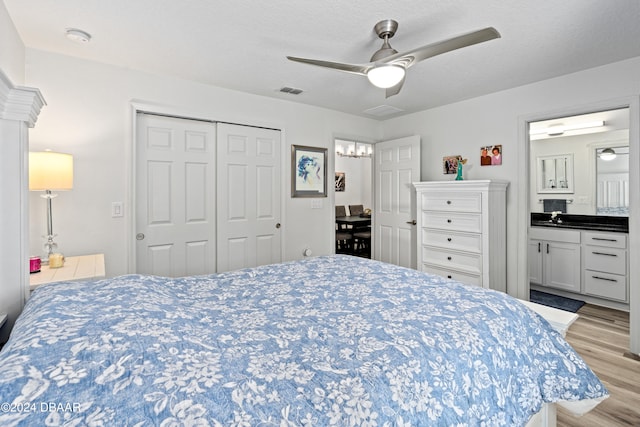 bedroom featuring a closet, connected bathroom, a textured ceiling, ceiling fan, and light hardwood / wood-style flooring