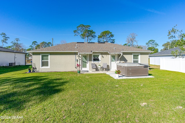 back of house with central air condition unit, a yard, a hot tub, and a patio area