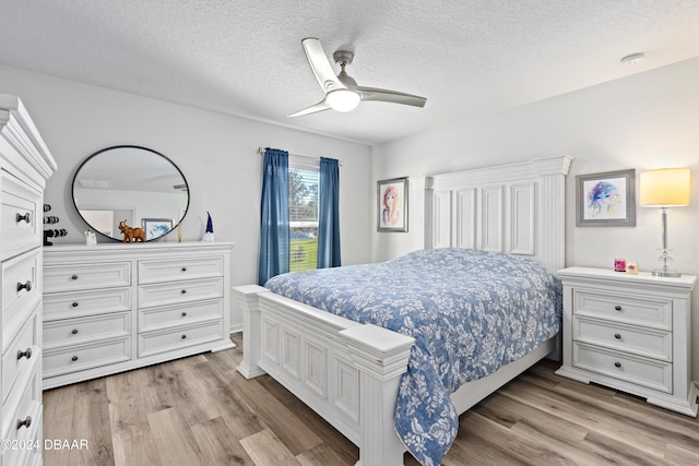 bedroom with a textured ceiling, light hardwood / wood-style floors, and ceiling fan