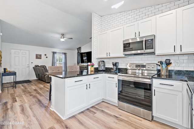 kitchen with white cabinetry, appliances with stainless steel finishes, ceiling fan, light wood-type flooring, and vaulted ceiling