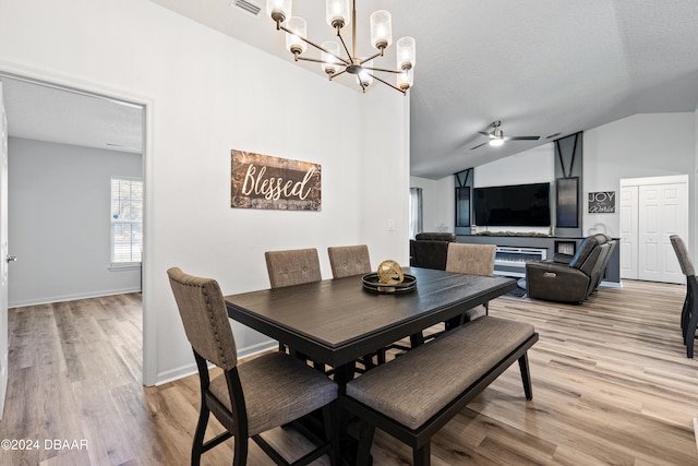 dining space featuring light hardwood / wood-style flooring, lofted ceiling, a textured ceiling, and ceiling fan with notable chandelier