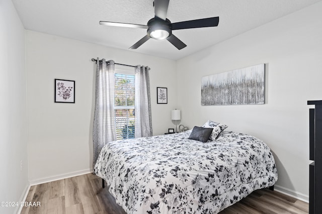 bedroom with a textured ceiling, hardwood / wood-style floors, and ceiling fan