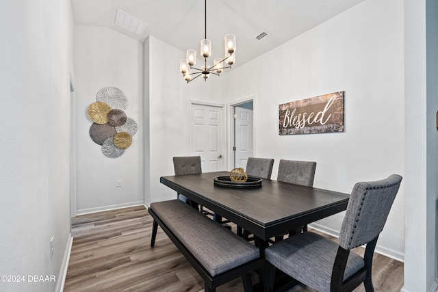 dining space featuring hardwood / wood-style floors, a chandelier, and lofted ceiling