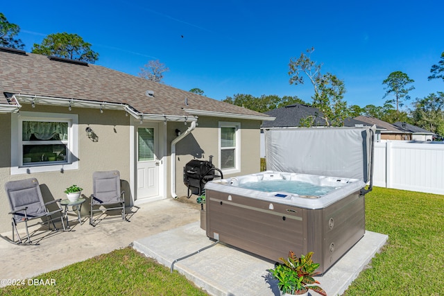 back of property with a hot tub, a patio area, and a yard