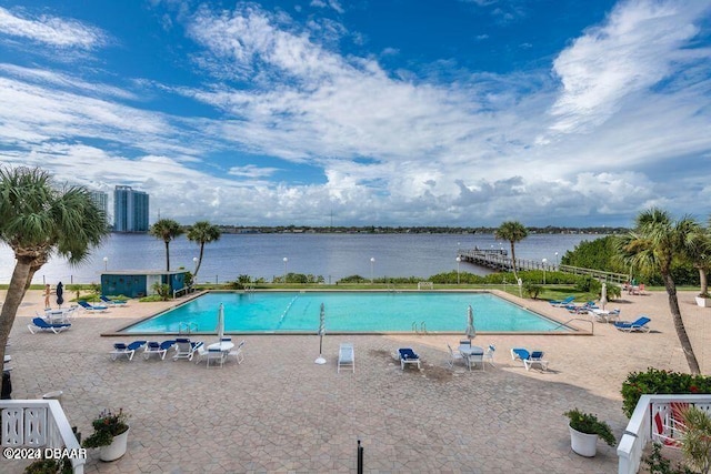 view of swimming pool with a patio area and a water view