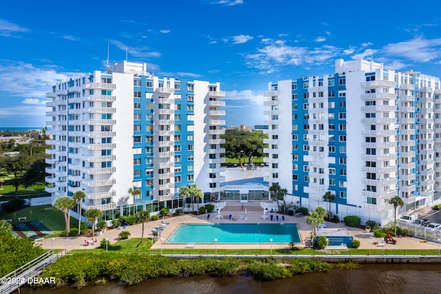 view of building exterior with a water view and a community pool