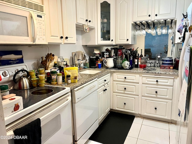 kitchen with light stone counters, light tile patterned floors, sink, white cabinetry, and white appliances