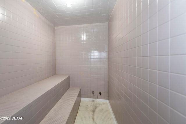 bathroom with tile walls and tiled shower