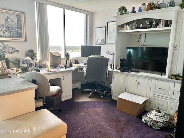 office space featuring a textured ceiling, built in desk, and dark carpet