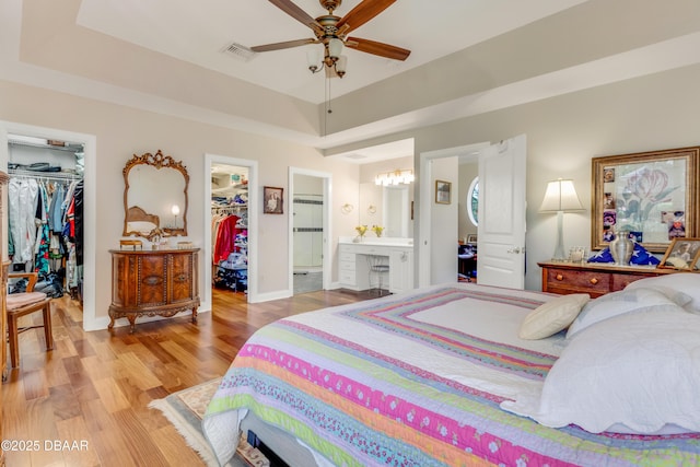 203 Prestwick Dr, New Smyrna Beach, FL 32168 - bedroom featuring a spacious closet, light wood finished floors, a closet, ensuite bath, and a chandelier