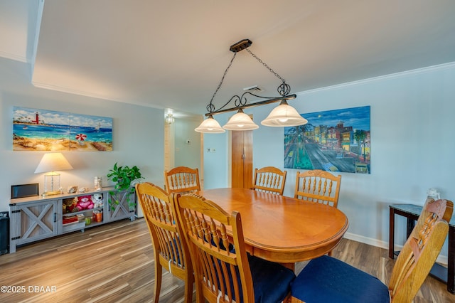 dining room featuring ornamental molding, baseboards, and wood finished floors