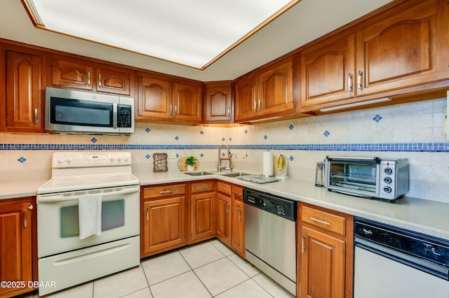 kitchen with brown cabinetry, a toaster, a sink, light countertops, and appliances with stainless steel finishes