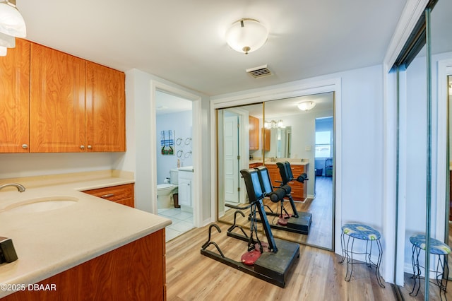 interior space featuring brown cabinetry, light wood-style flooring, light countertops, and a sink