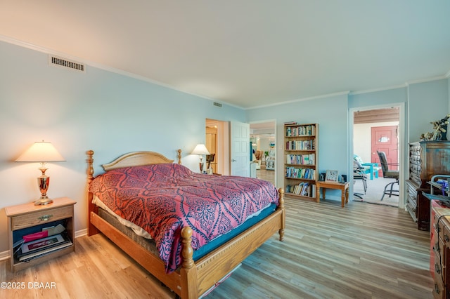 bedroom featuring visible vents, baseboards, wood finished floors, and crown molding