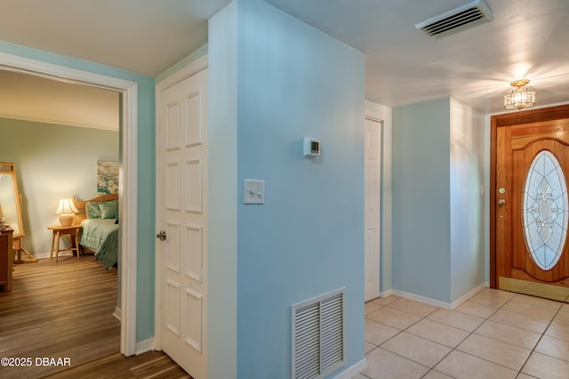 foyer with a chandelier, visible vents, baseboards, and light tile patterned flooring