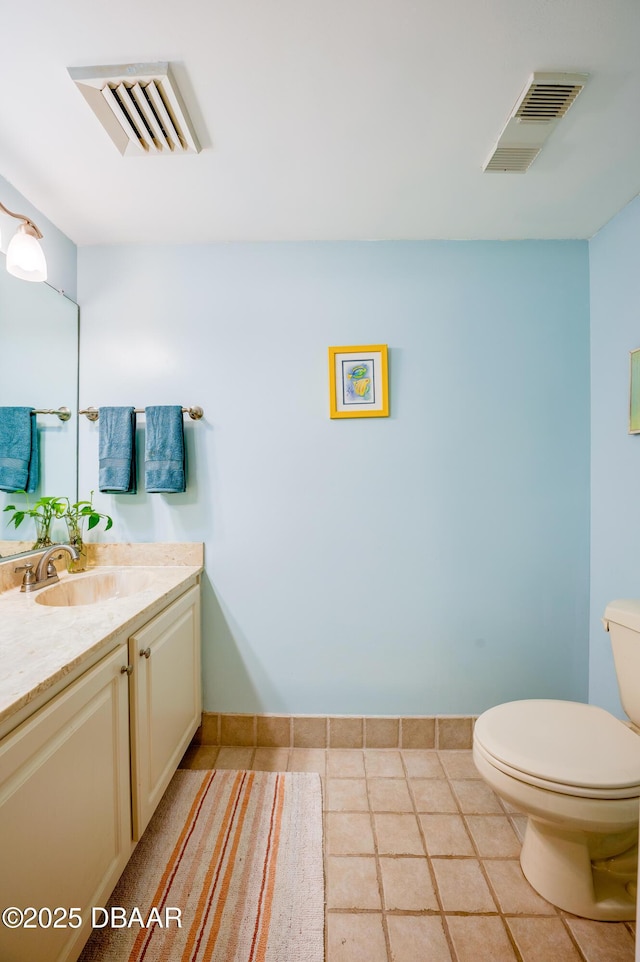 bathroom with vanity, toilet, baseboards, and visible vents