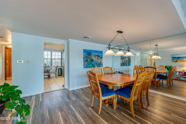 dining room featuring visible vents, crown molding, baseboards, and wood finished floors