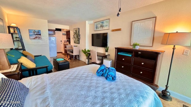 bedroom featuring white fridge and a textured ceiling