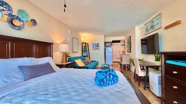 tiled bedroom with a textured ceiling and stainless steel refrigerator