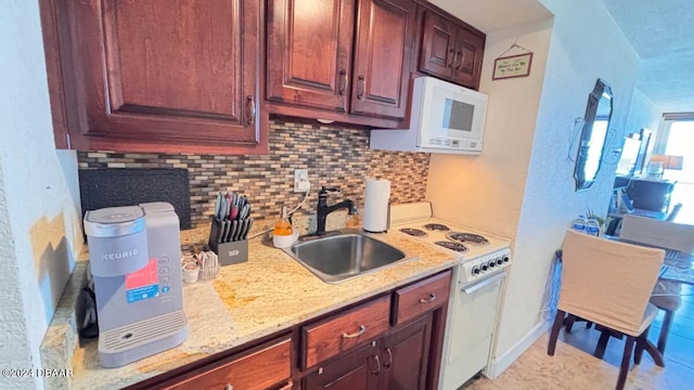 kitchen with light stone countertops, white appliances, tasteful backsplash, and sink