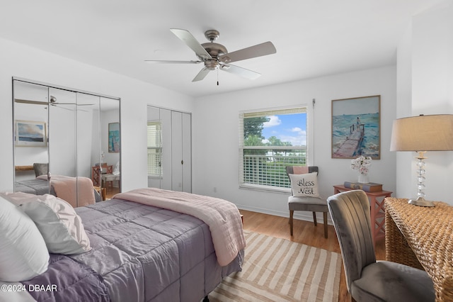 bedroom with ceiling fan, light wood-type flooring, and two closets