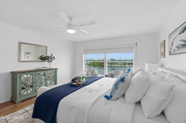 bedroom with ceiling fan, hardwood / wood-style floors, and a water view