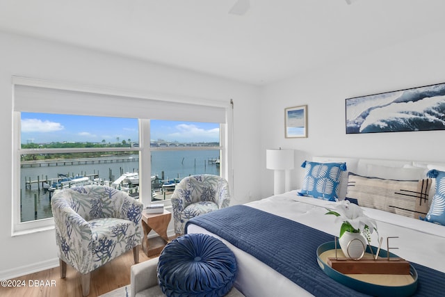 bedroom with hardwood / wood-style floors, a water view, and multiple windows