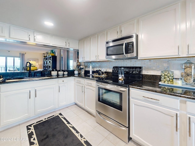 kitchen featuring dark stone counters, sink, light tile patterned floors, white cabinetry, and stainless steel appliances