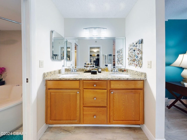 bathroom with vanity, a bath, and a textured ceiling