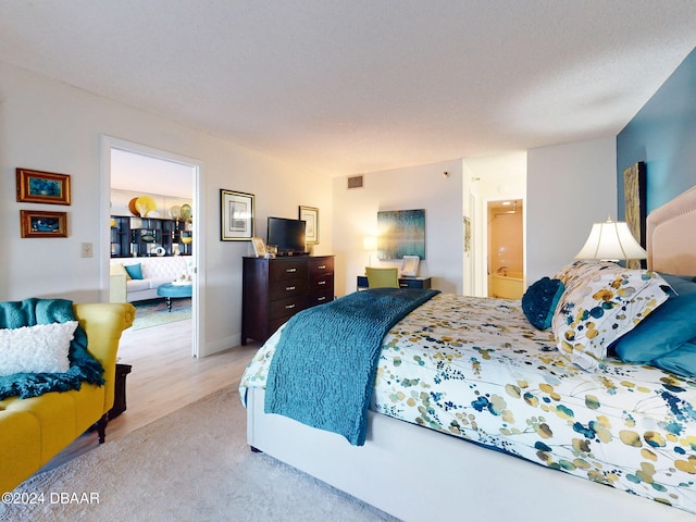 bedroom with ensuite bathroom and light hardwood / wood-style flooring